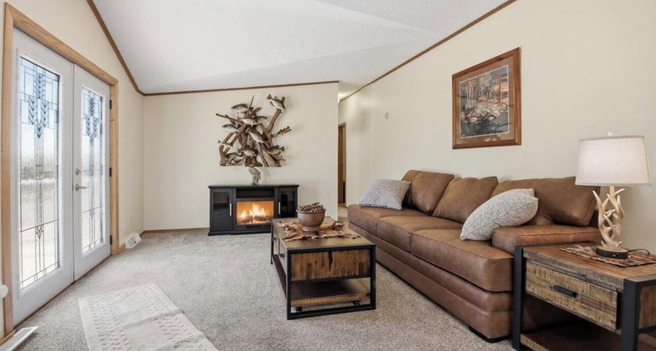 A living room with a fireplace, a brown leather sofa, a coffee table, and a lamp.