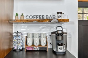 A coffee bar area with a coffee machine, a mug rack, and a coffee press on a counter. - Twilight Timber at Saluda Mountain Retreats! (Saluda)