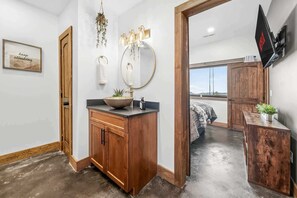 A modern bathroom with a wooden vanity, a large mirror, and a hanging plant. - Twilight Timber at Saluda Mountain Retreats! (Saluda)