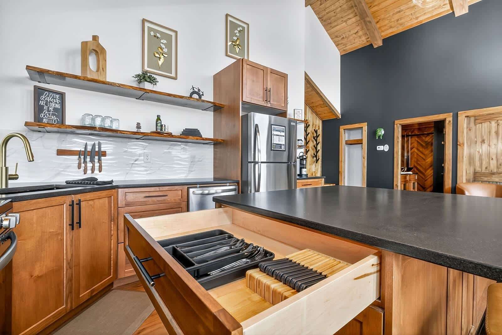 A modern kitchen with wooden cabinets, a stainless steel refrigerator, and a built-in knife block.