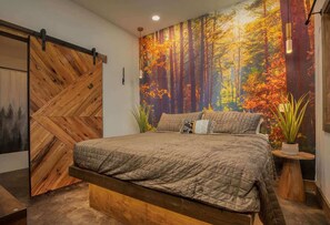 Ein Schlafzimmer mit einem Bett, einem Holz-Kopfteil, einer Wandmalerei und einem Nachttisch mit einer Pflanze.