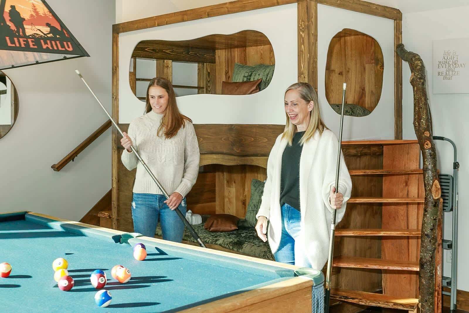 Una mesa de billar con bolas, un cabecero de madera y una escalera.
