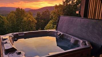A hot tub with a wooden exterior, surrounded by a wooden deck, and a sign indicating safety rules.