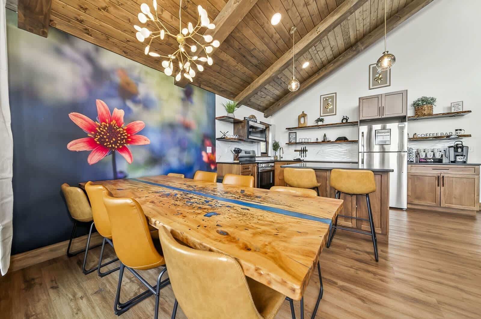 A modern kitchen with a central island, wooden flooring, and a dining area with a large table and chairs.