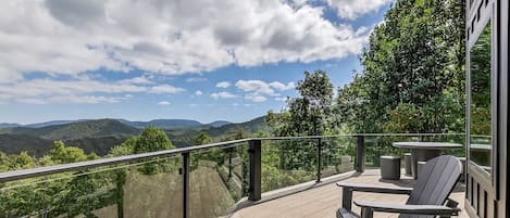 A deck with outdoor furniture overlooking a mountainous landscape.