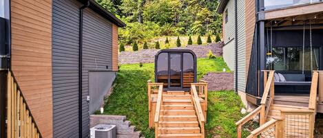 A modern outdoor staircase leading to a deck area with a view of a landscaped garden and a building with large windows.