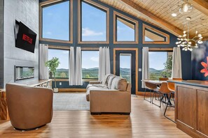 Ein geräumiger Wohnbereich mit Kamin, großen Fenstern und Blick ins Freie.