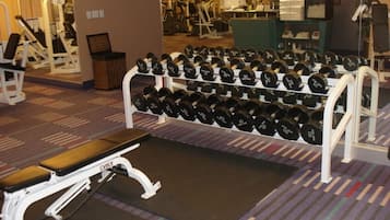 Ein Fitnessraum mit einer Bank, Kurzhanteln und Trainingsgeräten.