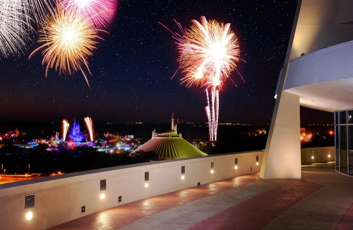 ’s Nachts een uitzicht op een gebouw met balkon, uitkijkend over een stadslandschap met vuurwerk.
