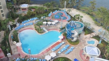 A resort with a large central pool, a water slide, and multiple sun loungers.