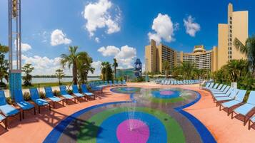 A hotel pool area with lounge chairs, a water feature, and a view of the ocean.