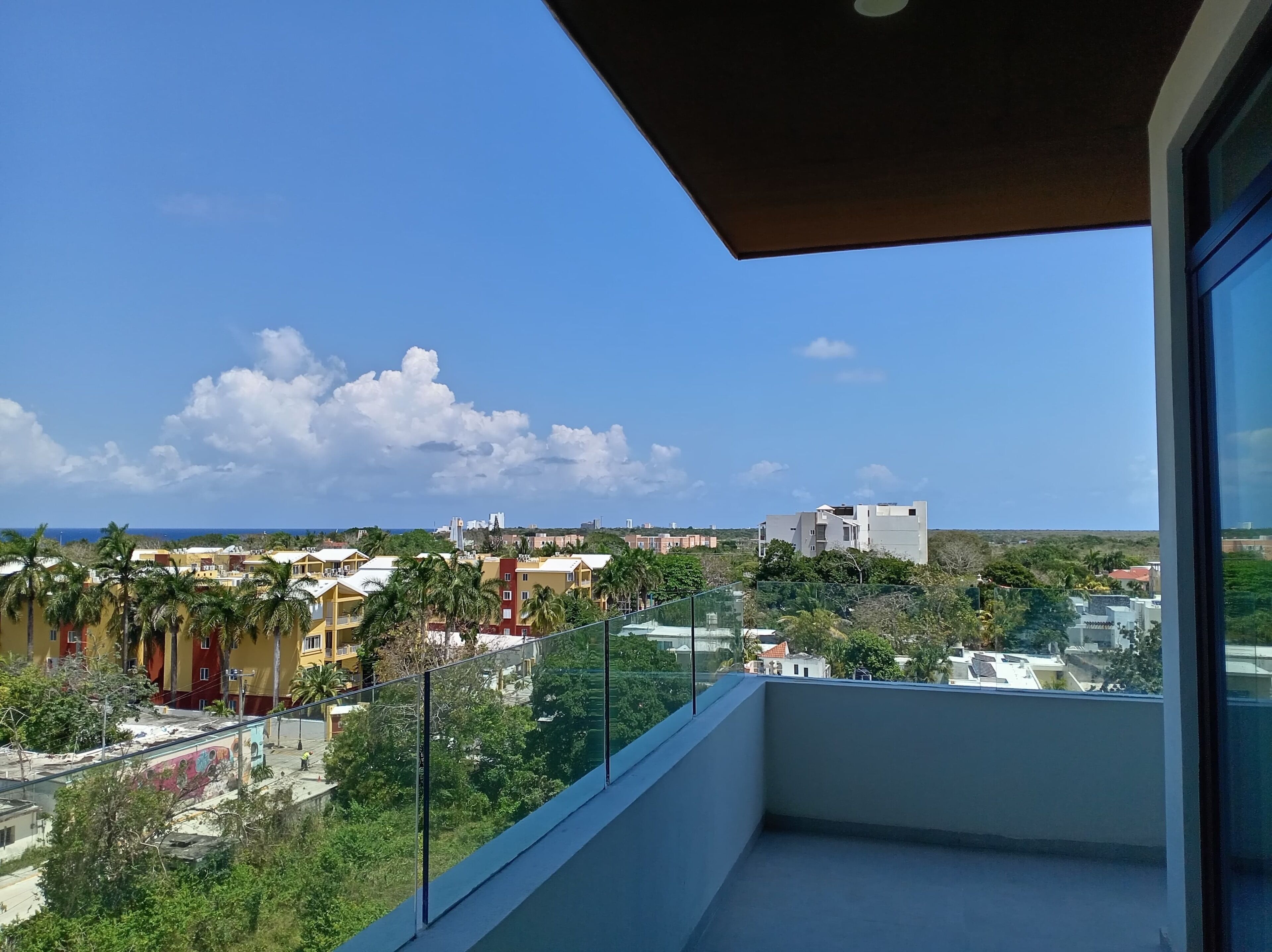 A balcony with a clear view of a cityscape, including buildings and a distant coastline.