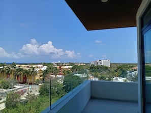 Ein Balkon mit freiem Blick auf eine Stadtlandschaft, einschließlich Gebäude und einer entfernten Küste.
