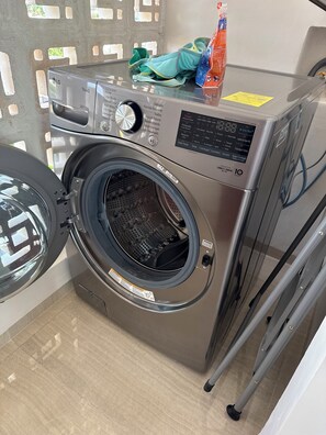 A front-loading LG ThinQ washing machine with a control panel, a detergent bottle, and a pair of green socks on top. - Galia Cozumel  (Cozumel)