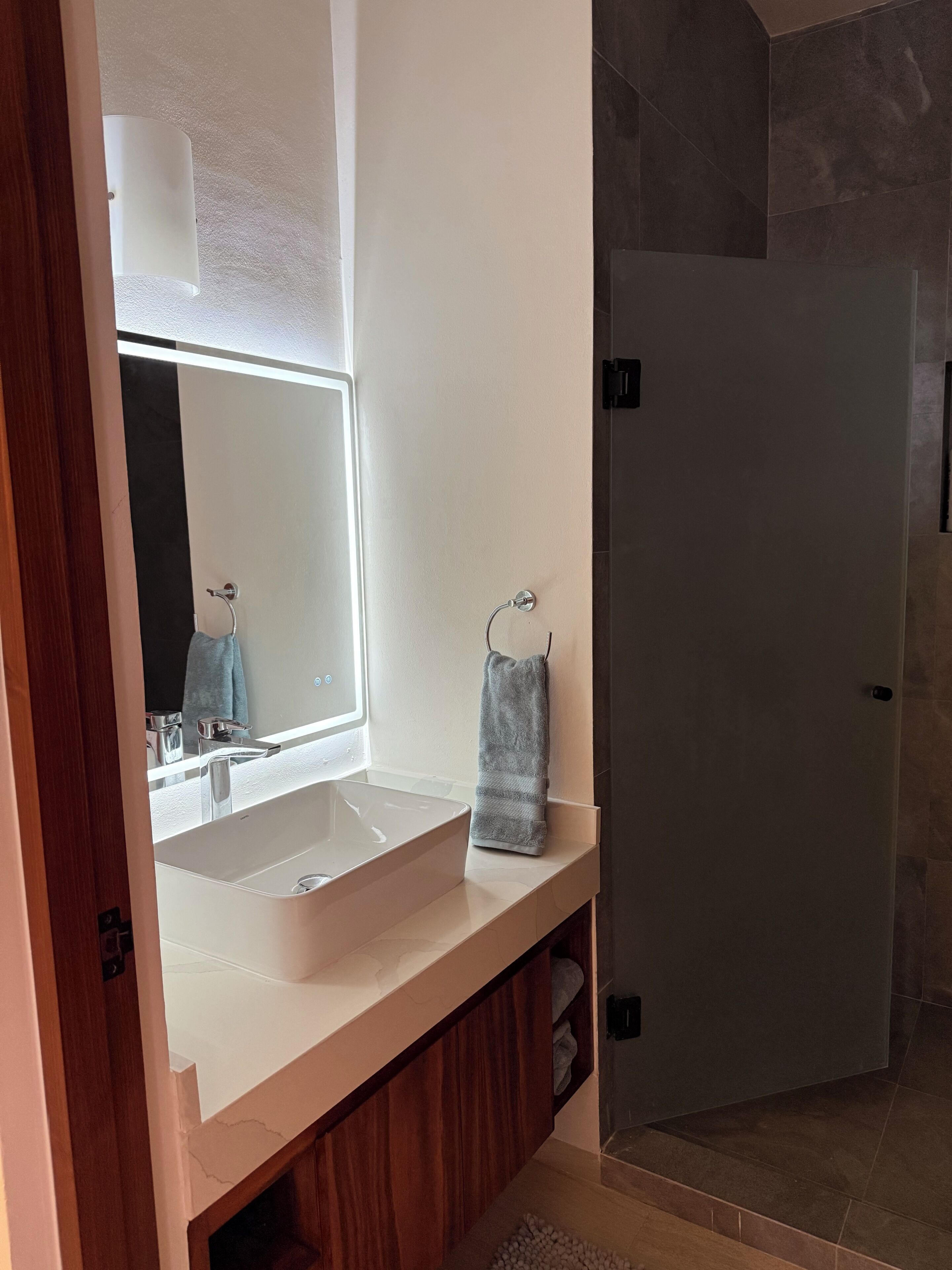 A bathroom with a white sink, a mirror, and a towel rack.