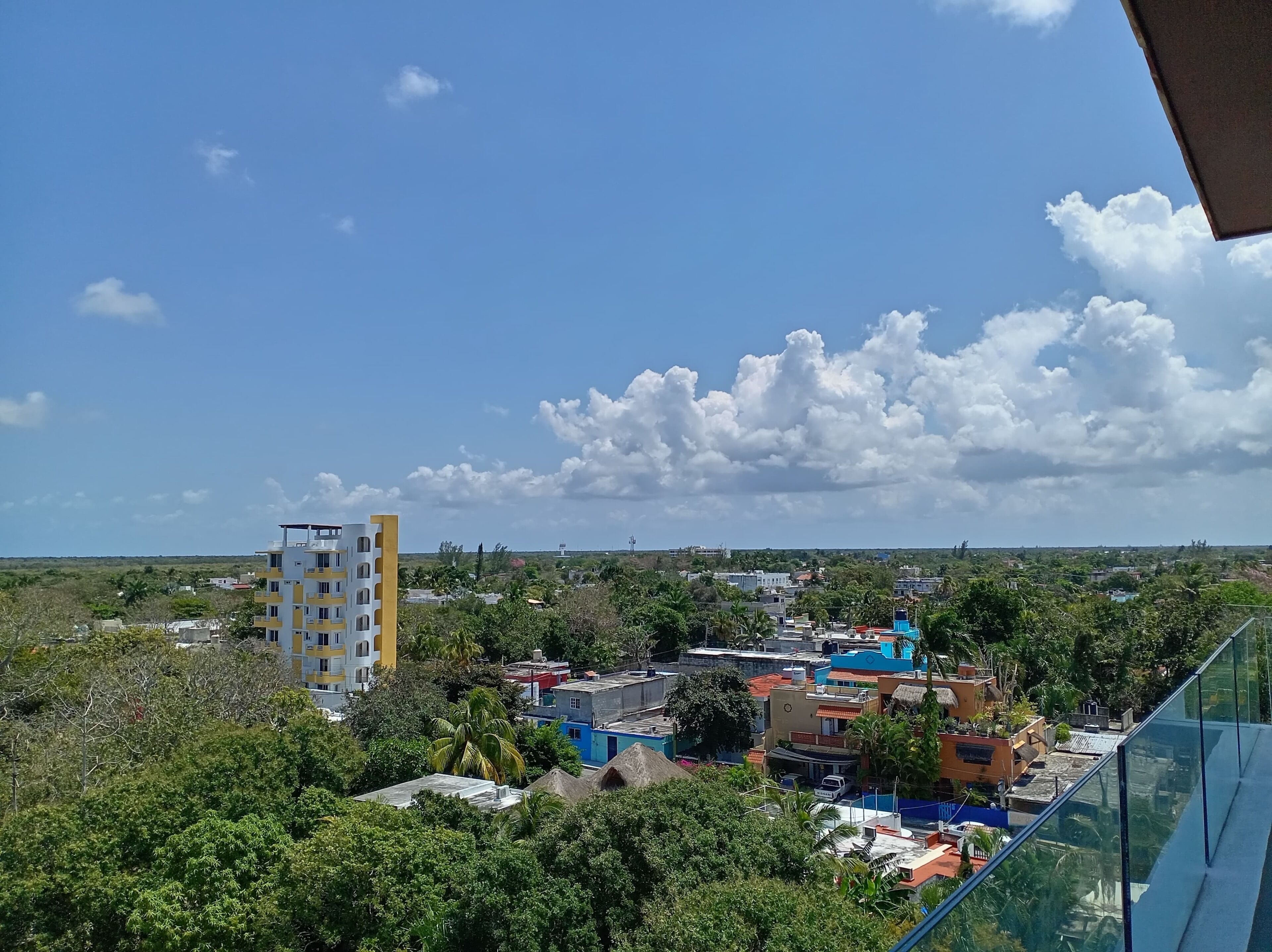 Un quartier résidentiel avec des immeubles à plusieurs étages, une végétation luxuriante et un ciel dégagé.