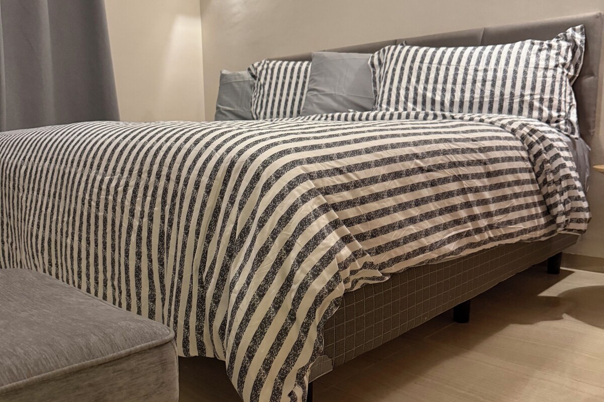 A modern bedroom with a bed, a bedside table, and a wall-mounted light fixture.