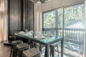 A dining area with a glass table and metal chairs, a fireplace, and a view of trees through large windows. - Spacious 2BR + Loft Mammoth Escape 680 (Mammoth Lakes)