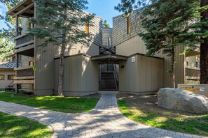 A modern building with a brick facade, a central entrance with a staircase, and a paved pathway leading to the entrance. - Spacious 2BR + Loft Mammoth Escape 680 (Mammoth Lakes)