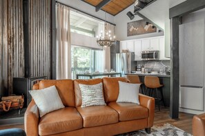 A modern living room with a leather sofa, a dining area, and a kitchen with stainless steel appliances. - Spacious 2BR + Loft Mammoth Escape 680 (Mammoth Lakes)