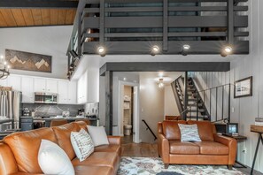 Een modern interieur met een trap, leren banken en een keukenhoek.