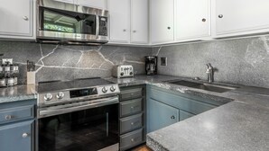 Een moderne keuken met een roestvrijstalen fornuis, magnetron en oven.