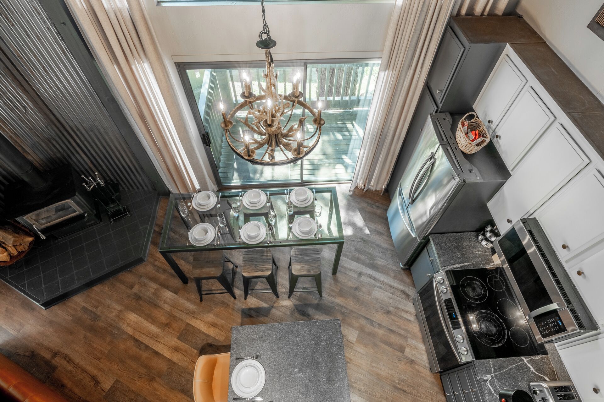A modern kitchen with a dining area, a chandelier, and a view of the outdoors.