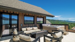 Un espace de vie extérieur moderne, doté d’un ensemble de canapés, d’un jacuzzi et offrant une vue sur les montagnes.