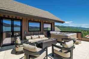 A modern outdoor living space with a sofa set, a hot tub, and a view of the mountains. - Close to Gondola Townhome 1097 (Steamboat Springs)