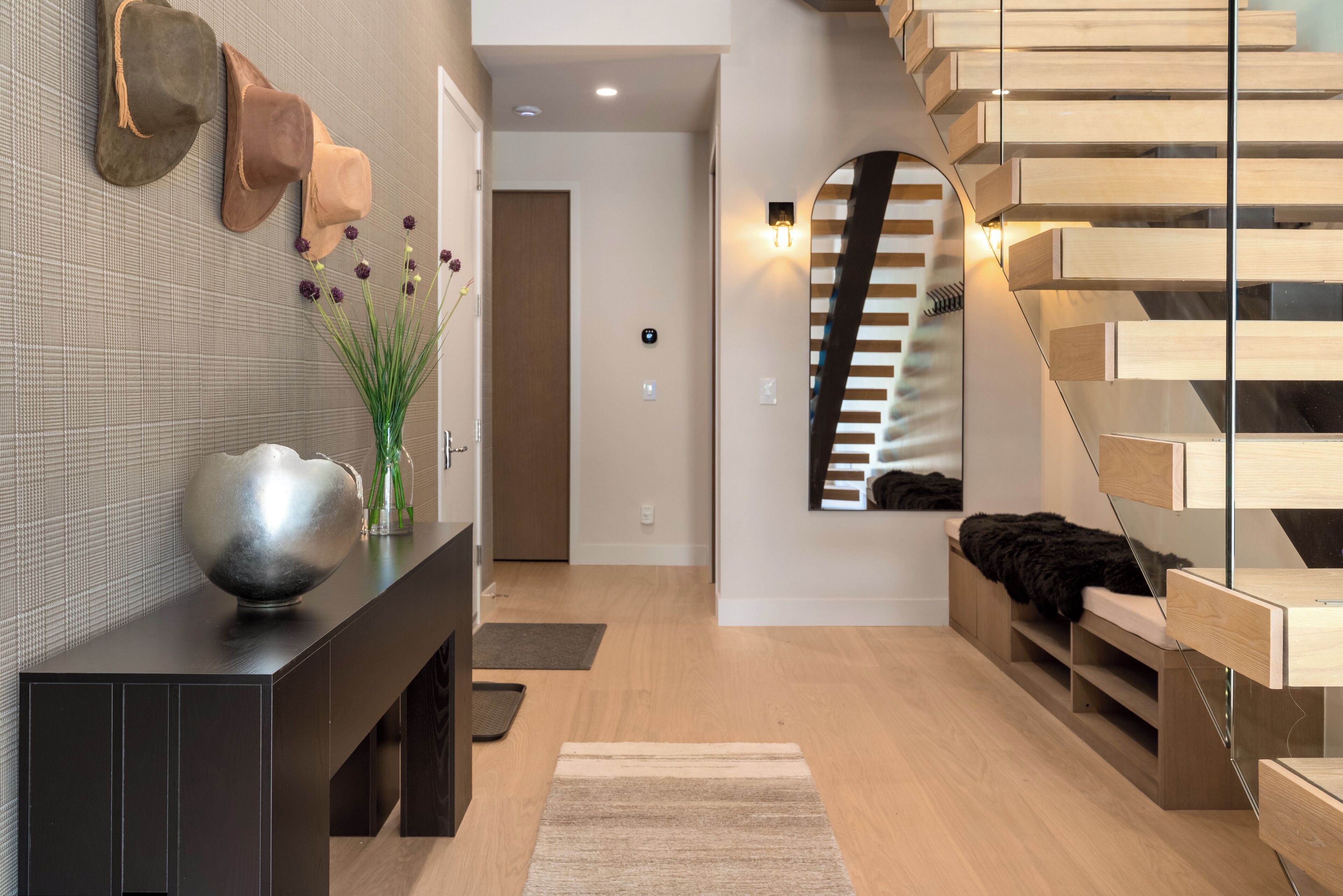 A modern interior with a wooden staircase, a console table with decorative items, and a minimalist design.