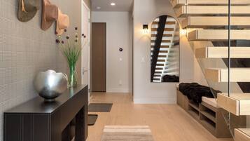 A modern interior with a wooden staircase, a console table with decorative items, and a minimalist design.