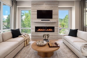 A modern living room with a fireplace, a flat-screen TV, and a chessboard on a coffee table. - Close to Gondola Townhome 1097 (Steamboat Springs)