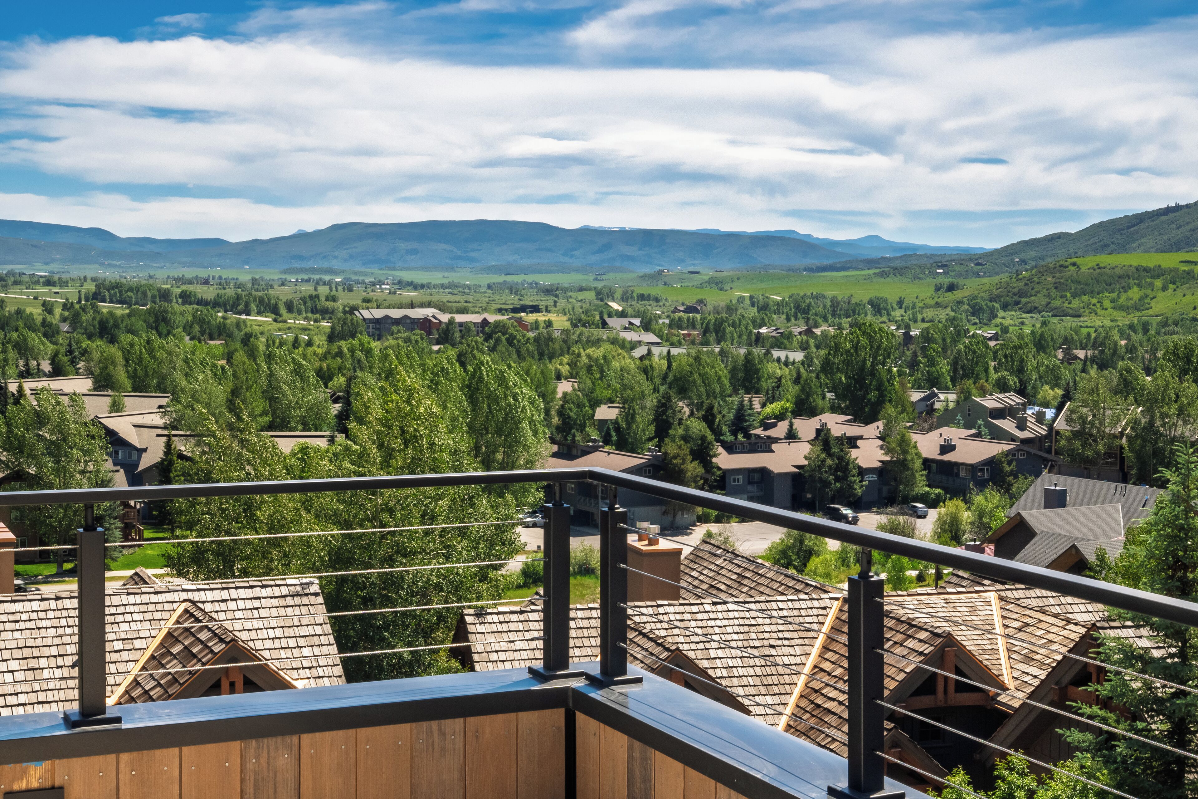 A residential area with multiple houses, a clear sky, and distant mountains.
