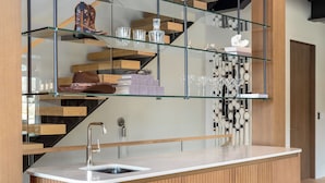 A modern kitchen with a built-in sink, wooden cabinetry, and a glass shelf displaying various items. - Close to Ski Townhome 1096 (Steamboat Springs)