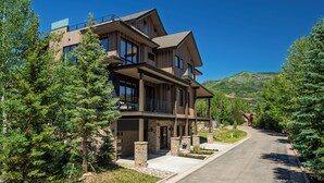 A modern multi-story house with a spacious driveway, surrounded by evergreen trees. - Close to Ski Townhome 1096 (Steamboat Springs)