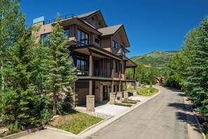 A modern multi-story house with a spacious driveway, surrounded by evergreen trees. - Close to Ski Townhome 1096 (Steamboat Springs)