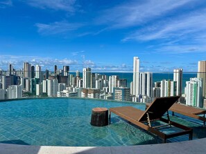 A rooftop infinity pool with lounge chairs and a cityscape view. - Studio de luxo no Praia de Gameleira (Recife)