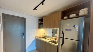 Una cocina compacta con refrigerador integrado, lavamanos y armarios de madera.