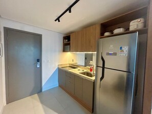 Eine kompakte Küche mit einem Einbaukühlschrank, einer Spüle und Holzschränken.