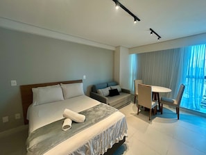 Ein Hotelzimmer mit Bett, Schreibtisch und Stuhl. Ein Fenster mit Vorhängen ist vorhanden.