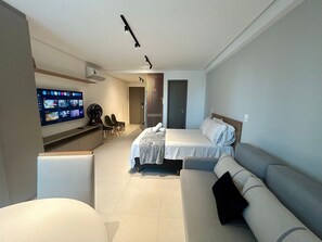 Een hotelkamer met een bed, een bank, een televisie en een bureau met stoelen.