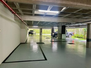 A multi-level parking garage with concrete pillars, a flat floor, and a ceiling with skylights. - Studio de luxo no Praia de Gameleira (Recife)