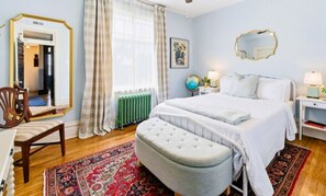 Ein Schlafzimmer mit Bett, Sessel, Bank, Globus und Spiegel.