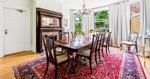 A dining room with a large wooden table, multiple chairs, a fireplace, and a view through large windows. - Historic 1910 Pittsburgh Victorian  (Pittsburgh)
