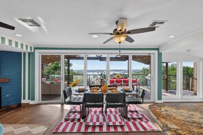 A dining area with a table set for four, a ceiling fan, and a view of the outdoors. - Wildlight House: Cascade | Canyon Lake | Sleeps 17 (Canyon Lake)