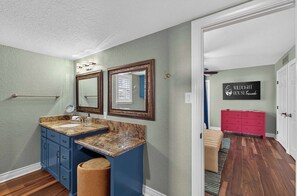 A bathroom with a double sink, vanity, and a mirror. There is a towel rack and a wall-mounted light fixture. - Wildlight House: Cascade | Canyon Lake | Sleeps 17 (Canyon Lake)