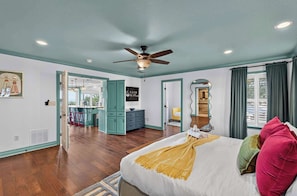 A bedroom with a bed, a ceiling fan, a large mirror, and a view of the bathroom. - Wildlight House: Cascade | Canyon Lake | Sleeps 17 (Canyon Lake)