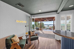 A room with a seating area, a bar counter, and a view of the outdoors. - Wildlight House: Cascade | Canyon Lake | Sleeps 17 (Canyon Lake)