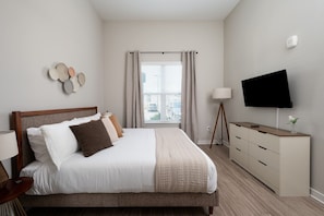 A bedroom with a bed, bedside table, lamp, TV, and a dresser. - Chic, New Apt | Pool | Long Stays (Athens)