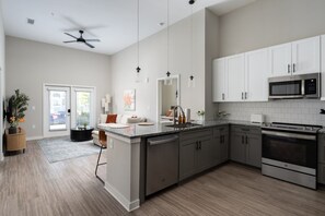 A modern kitchen with a central island, stainless steel appliances, and white cabinetry. - Chic, New Apt | Pool | Long Stays (Athens)